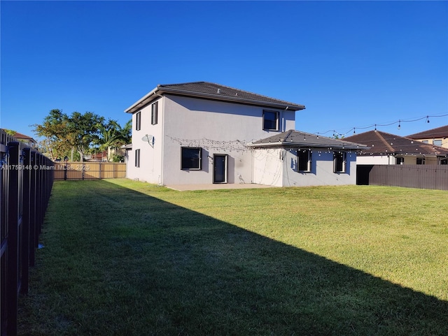 rear view of property featuring a yard, a fenced backyard, and stucco siding