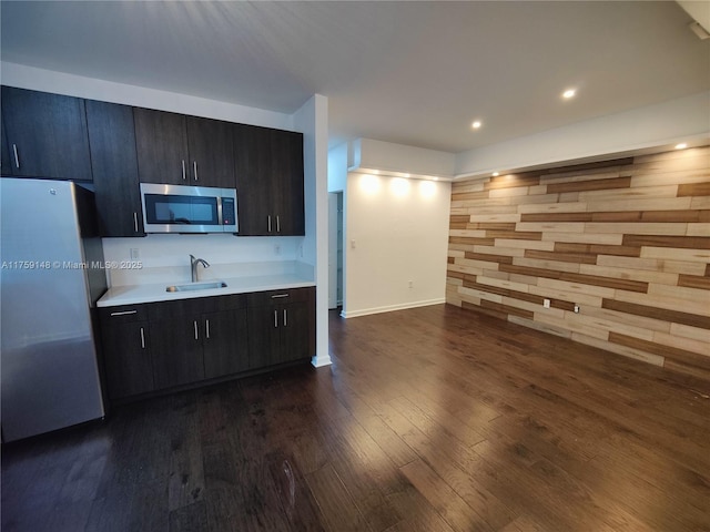 kitchen featuring dark wood-type flooring, a sink, stainless steel appliances, light countertops, and baseboards