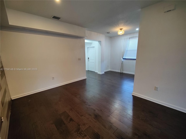 spare room featuring visible vents, dark wood-type flooring, and baseboards