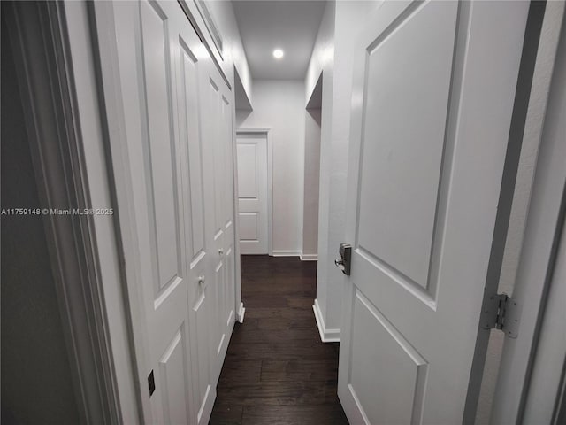 corridor featuring baseboards and dark wood-style floors