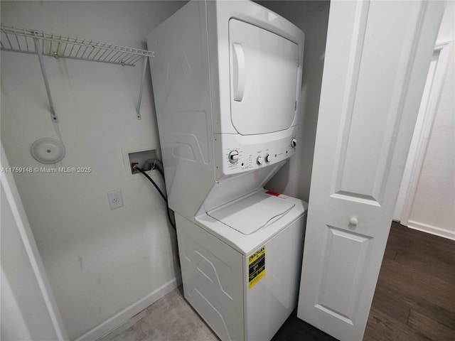 laundry room with laundry area, stacked washing maching and dryer, baseboards, and wood finished floors