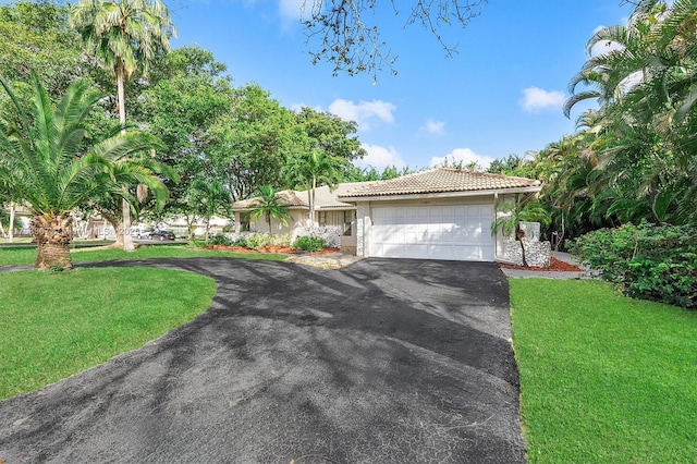 view of front of property with a garage, driveway, a front lawn, and a tile roof