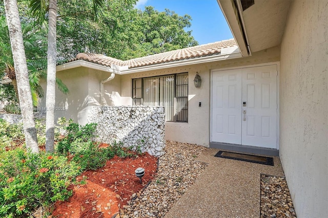 property entrance with stucco siding and a tiled roof