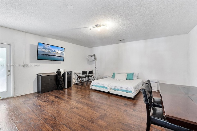 bedroom with a textured ceiling and wood finished floors