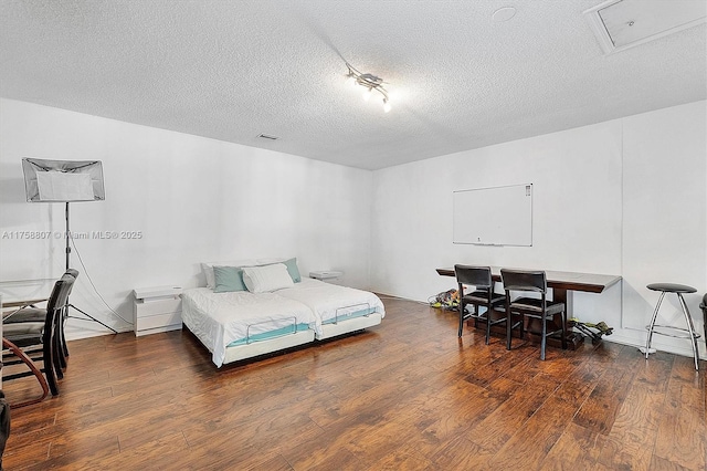 bedroom with a textured ceiling and wood finished floors