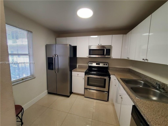 kitchen featuring white cabinets, light tile patterned floors, stainless steel appliances, and a sink