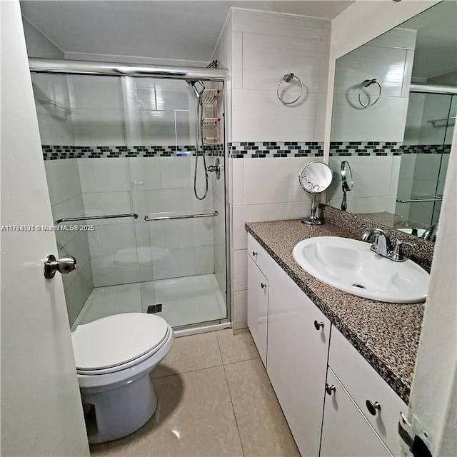 full bathroom with toilet, vanity, tile walls, tile patterned floors, and a stall shower