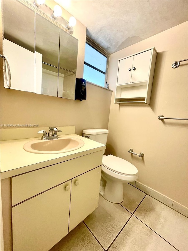 bathroom with vanity, baseboards, tile patterned flooring, a textured ceiling, and toilet