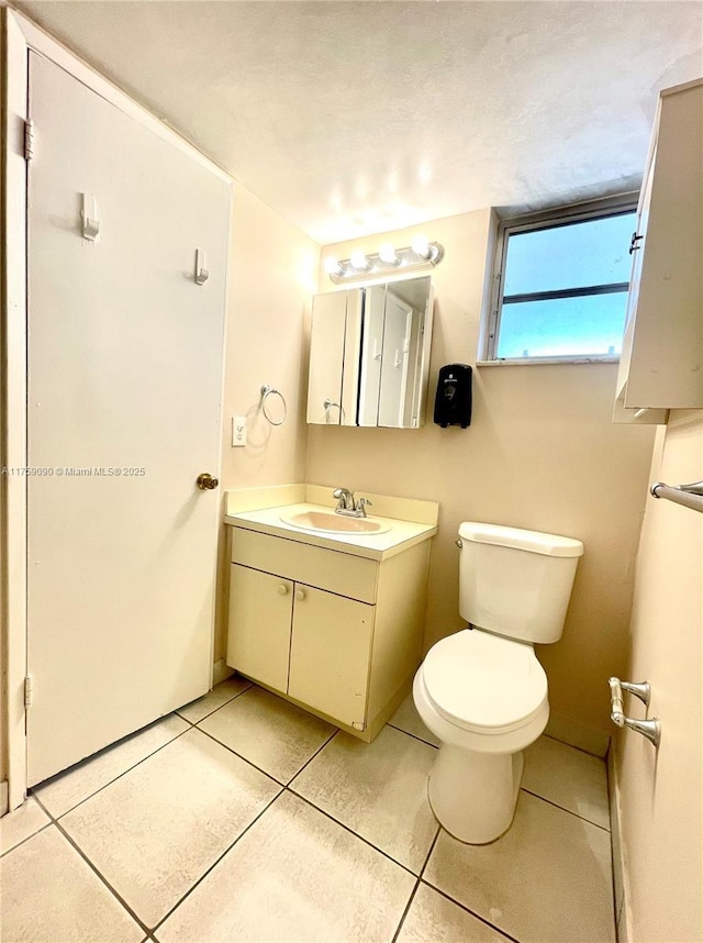 half bath with tile patterned flooring, toilet, and vanity