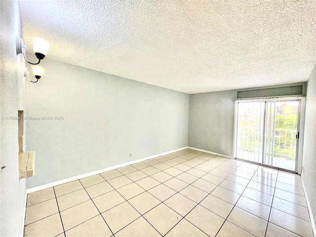 unfurnished room with light tile patterned floors, baseboards, and a textured ceiling