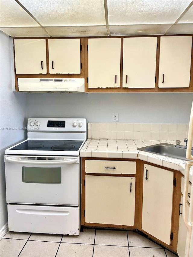 kitchen with tile counters, light tile patterned flooring, white electric range, and under cabinet range hood