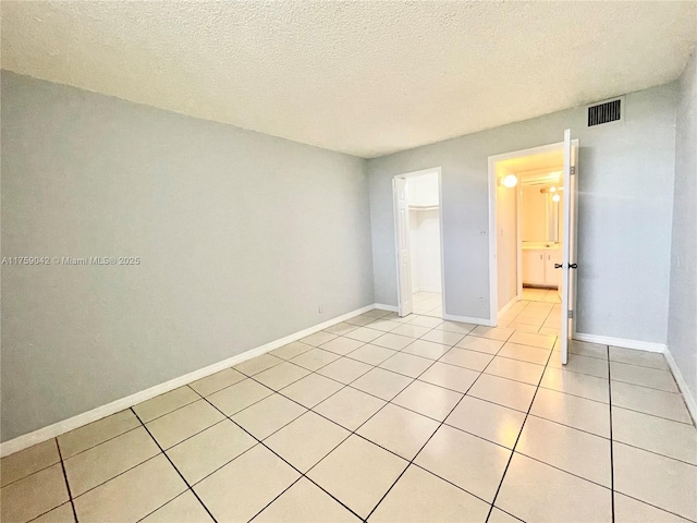 spare room with baseboards, a textured ceiling, and light tile patterned flooring