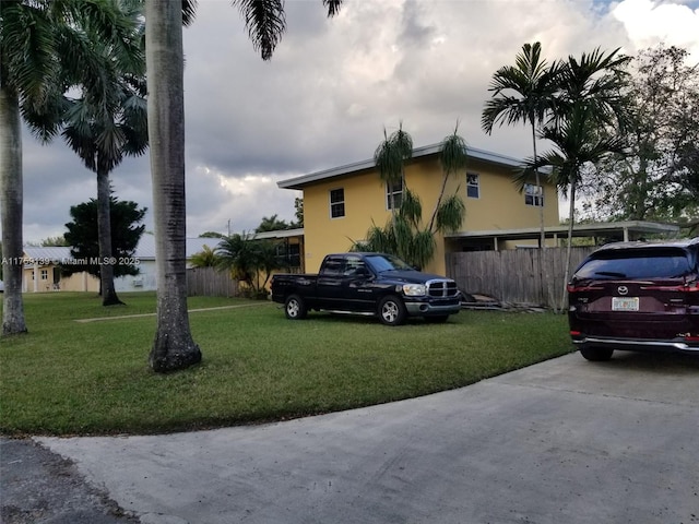 view of side of home featuring stucco siding, fence, and a yard