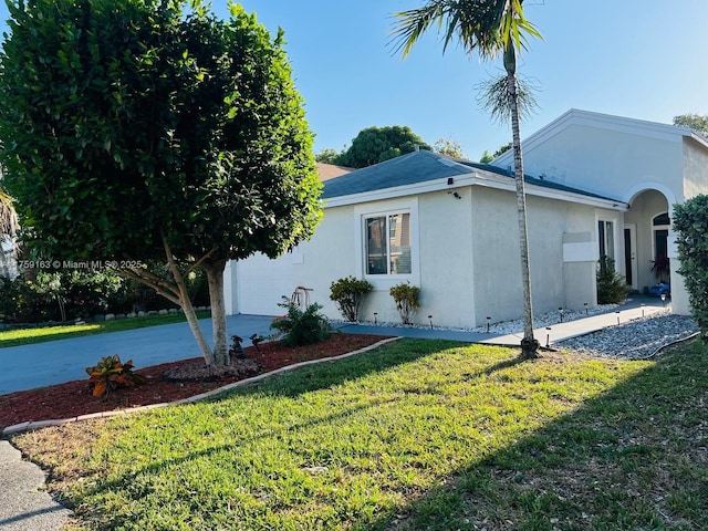 view of home's exterior with a garage, a lawn, driveway, and stucco siding