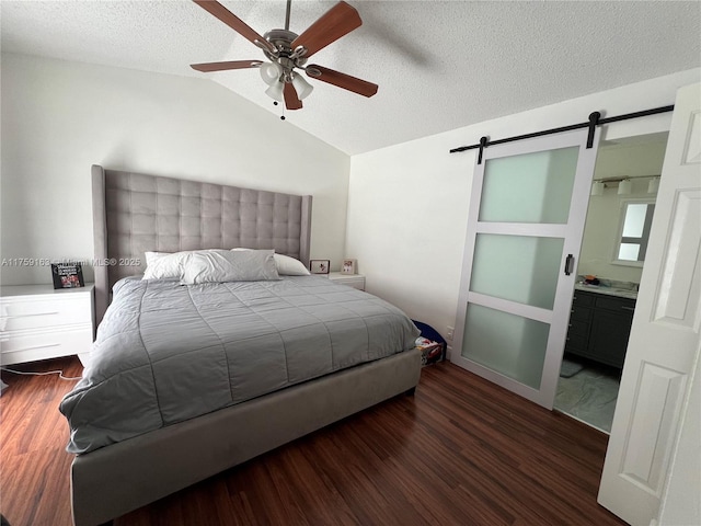 bedroom with a barn door, a ceiling fan, wood finished floors, vaulted ceiling, and a textured ceiling