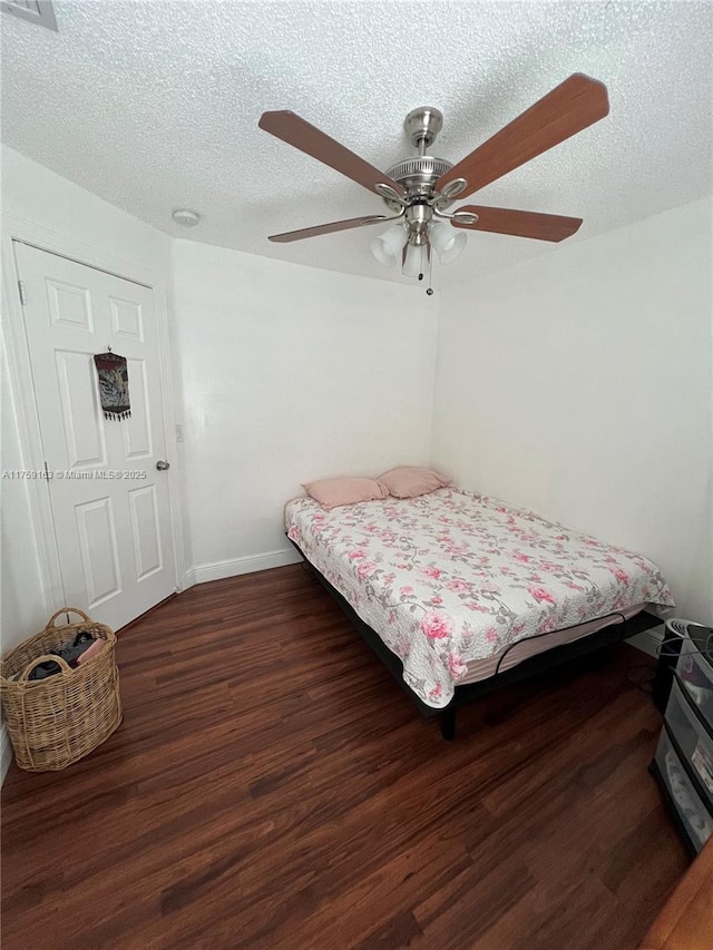 bedroom with wood finished floors, a textured ceiling, baseboards, and ceiling fan