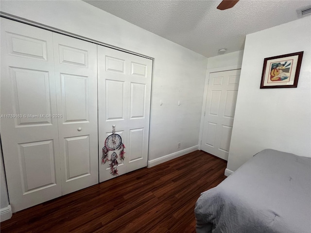 bedroom featuring dark wood-style flooring, a closet, visible vents, a textured ceiling, and baseboards