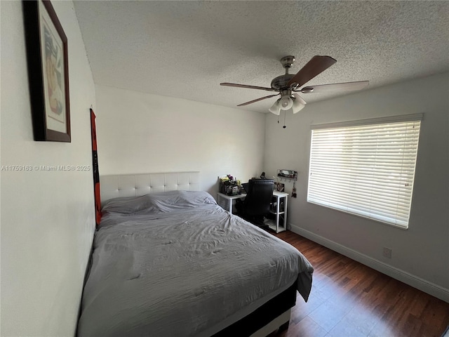 bedroom with ceiling fan, a textured ceiling, baseboards, and wood finished floors