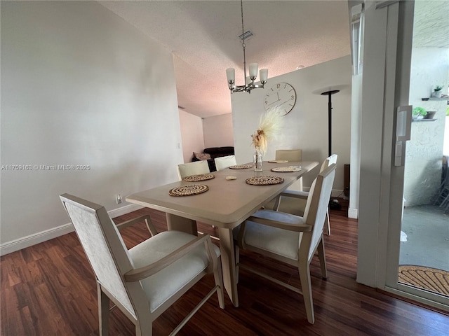 dining room with a notable chandelier, a textured ceiling, baseboards, and wood finished floors