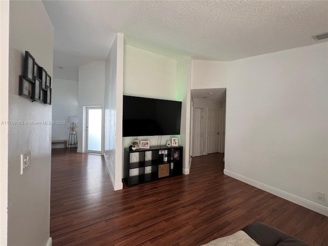 unfurnished living room featuring baseboards, wood finished floors, visible vents, and a textured ceiling