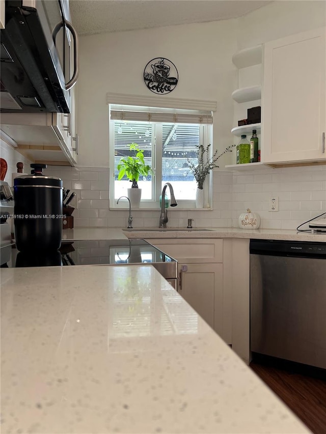 kitchen with backsplash, stainless steel dishwasher, white cabinetry, open shelves, and a sink