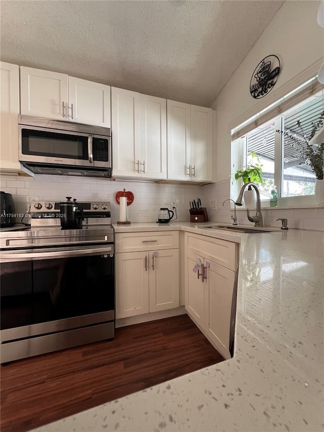 kitchen featuring appliances with stainless steel finishes, white cabinetry, a sink, and tasteful backsplash