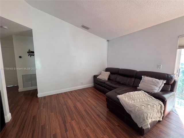 living area with baseboards, a textured ceiling, visible vents, and wood finished floors