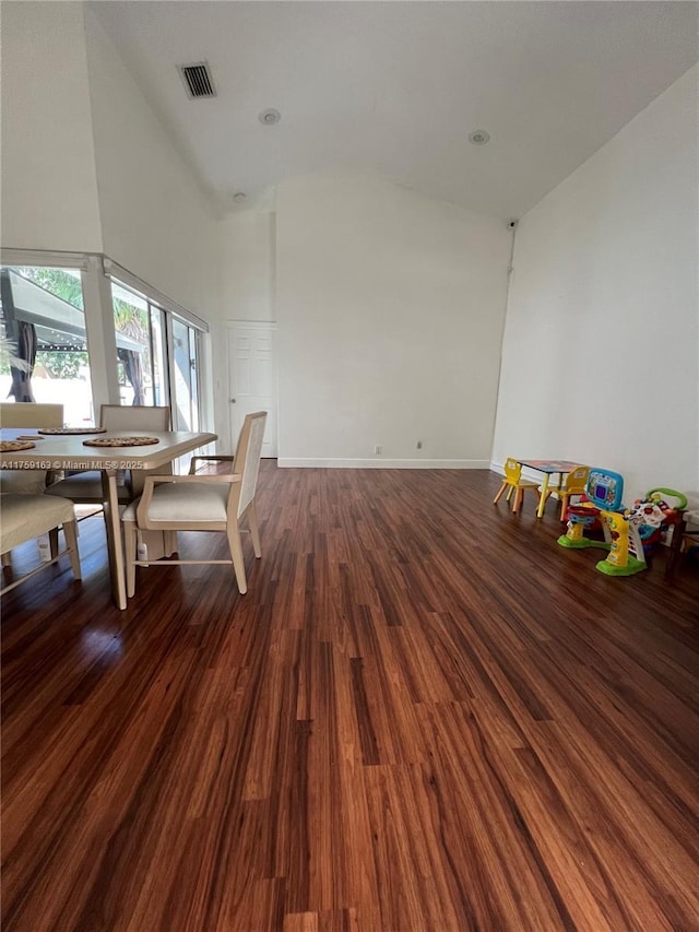 unfurnished dining area featuring baseboards, wood finished floors, visible vents, and high vaulted ceiling