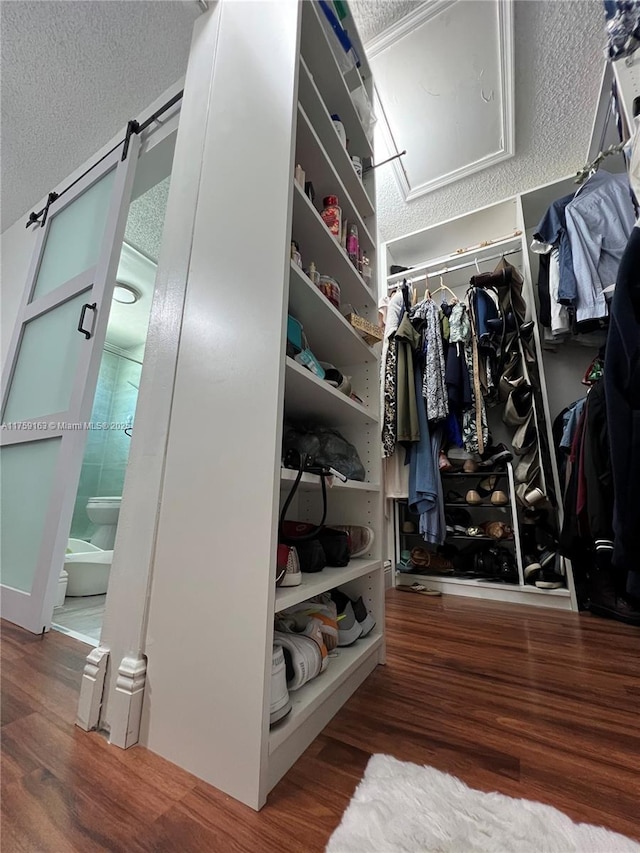 walk in closet with attic access and wood finished floors