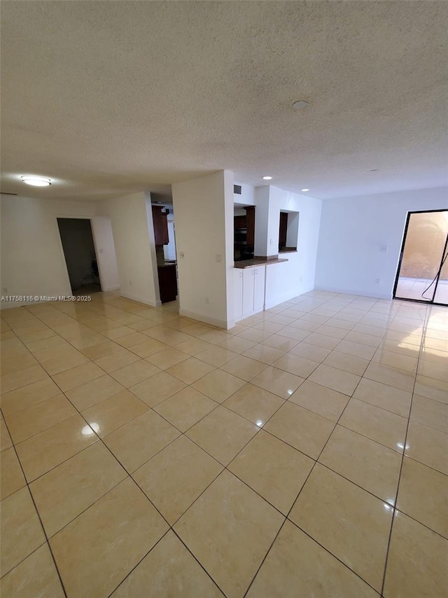 spare room featuring a textured ceiling and light tile patterned flooring