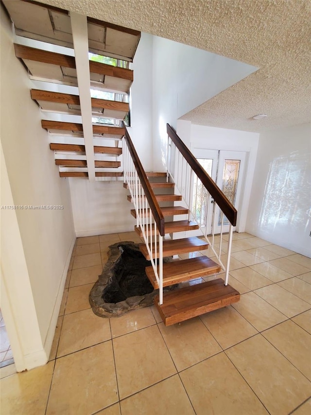 stairway with baseboards, a textured ceiling, and tile patterned floors