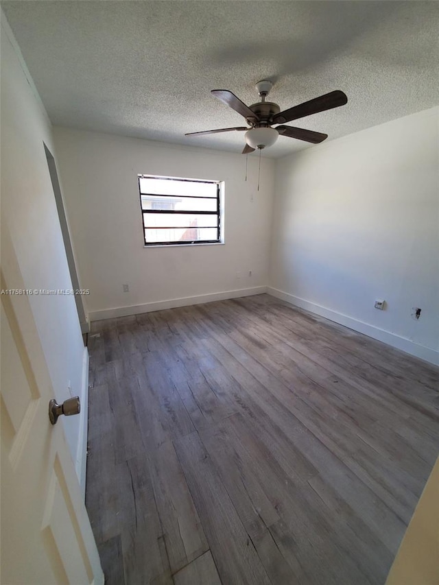 spare room featuring a textured ceiling, baseboards, and wood finished floors