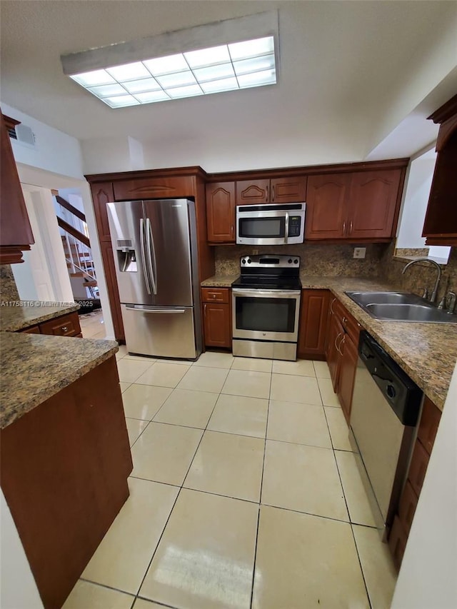 kitchen featuring appliances with stainless steel finishes, tasteful backsplash, a sink, and light tile patterned floors