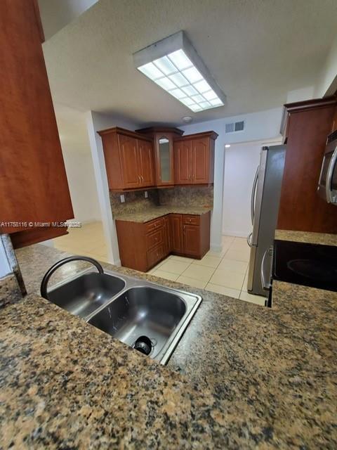 kitchen with light tile patterned floors, visible vents, glass insert cabinets, appliances with stainless steel finishes, and a sink