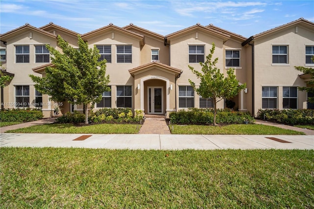 townhome / multi-family property with a front yard and stucco siding