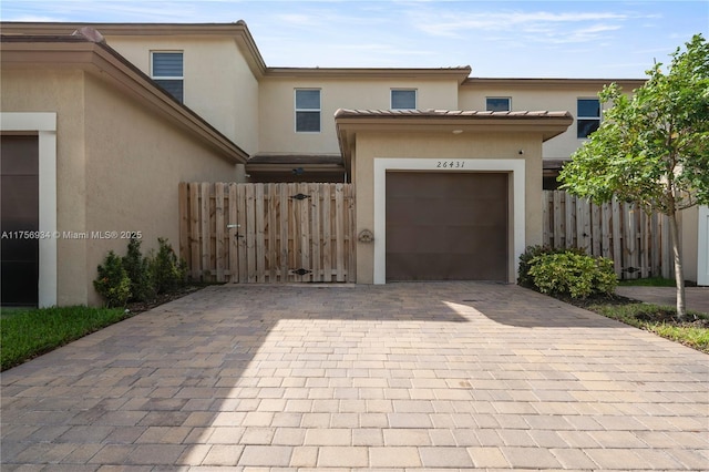 view of front of property featuring a garage, fence, decorative driveway, and stucco siding