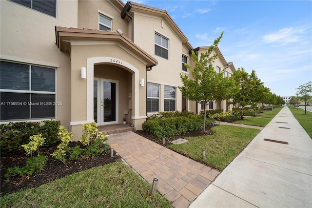 view of exterior entry with a yard and stucco siding