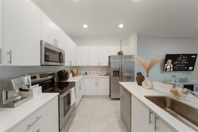 kitchen with white cabinets, stainless steel appliances, a sink, and light countertops