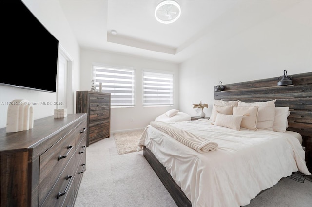 bedroom featuring baseboards, a tray ceiling, and light colored carpet