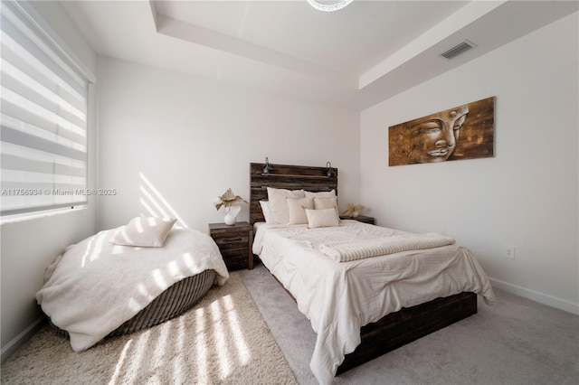 carpeted bedroom with baseboards, visible vents, and a tray ceiling