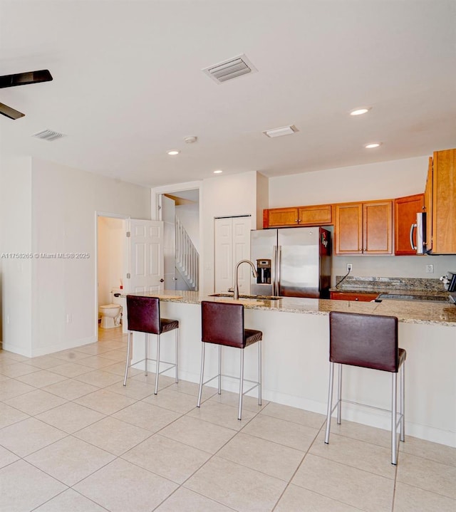 9399 W 33rd Ln # 1, Hialeah, FL 33018 - kitchen with visible vents, a sink, appliances with stainless steel finishes, brown cabinetry, and light stone countertops