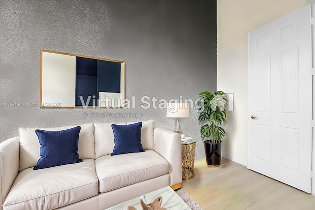 living area with baseboards, wood finished floors, and an accent wall