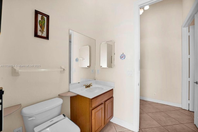 bathroom with baseboards, toilet, vanity, and tile patterned flooring