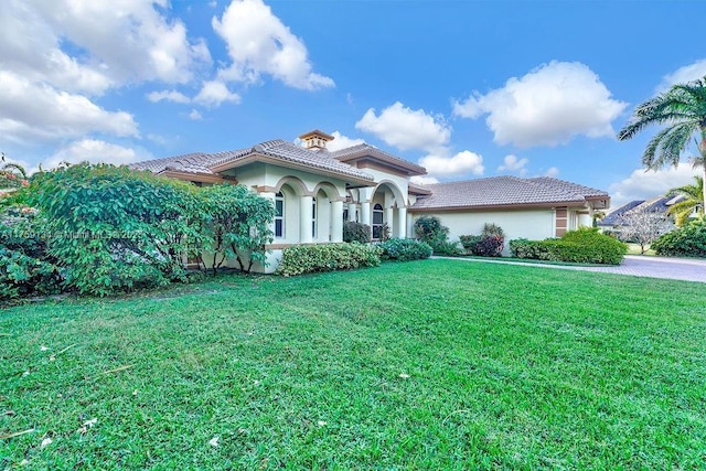 mediterranean / spanish-style house with stucco siding, a front yard, and a tile roof