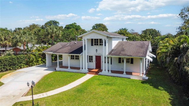 view of front of house with driveway, an attached carport, covered porch, a front yard, and stucco siding