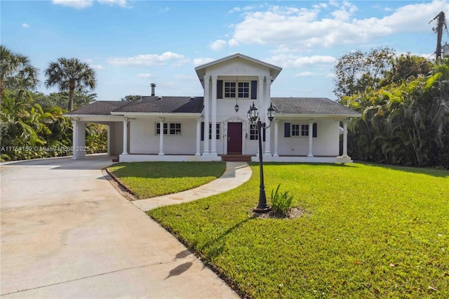 greek revival house featuring a carport, a front lawn, driveway, and stucco siding