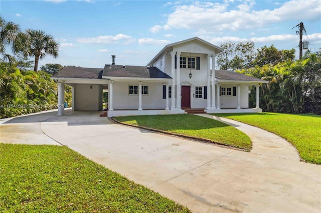 greek revival inspired property with concrete driveway, a front lawn, and stucco siding