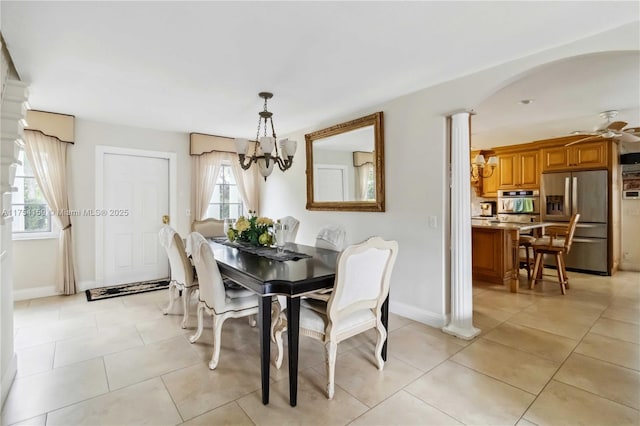 dining area with ceiling fan with notable chandelier, arched walkways, baseboards, and light tile patterned floors