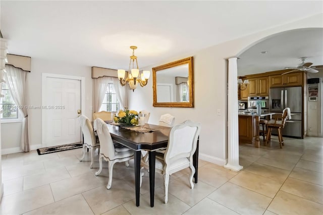 dining area with ceiling fan with notable chandelier, arched walkways, baseboards, and light tile patterned floors