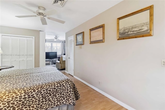 bedroom featuring baseboards, visible vents, a ceiling fan, light wood-type flooring, and two closets